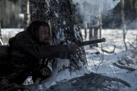 HD desktop wallpaper featuring Leonardo DiCaprio in a scene from the movie The Revenant, aiming a rifle while crouched in a snowy forest.