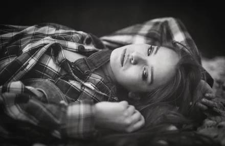 Black and white HD desktop wallpaper of a brunette woman lying down, gazing thoughtfully with a moody expression.