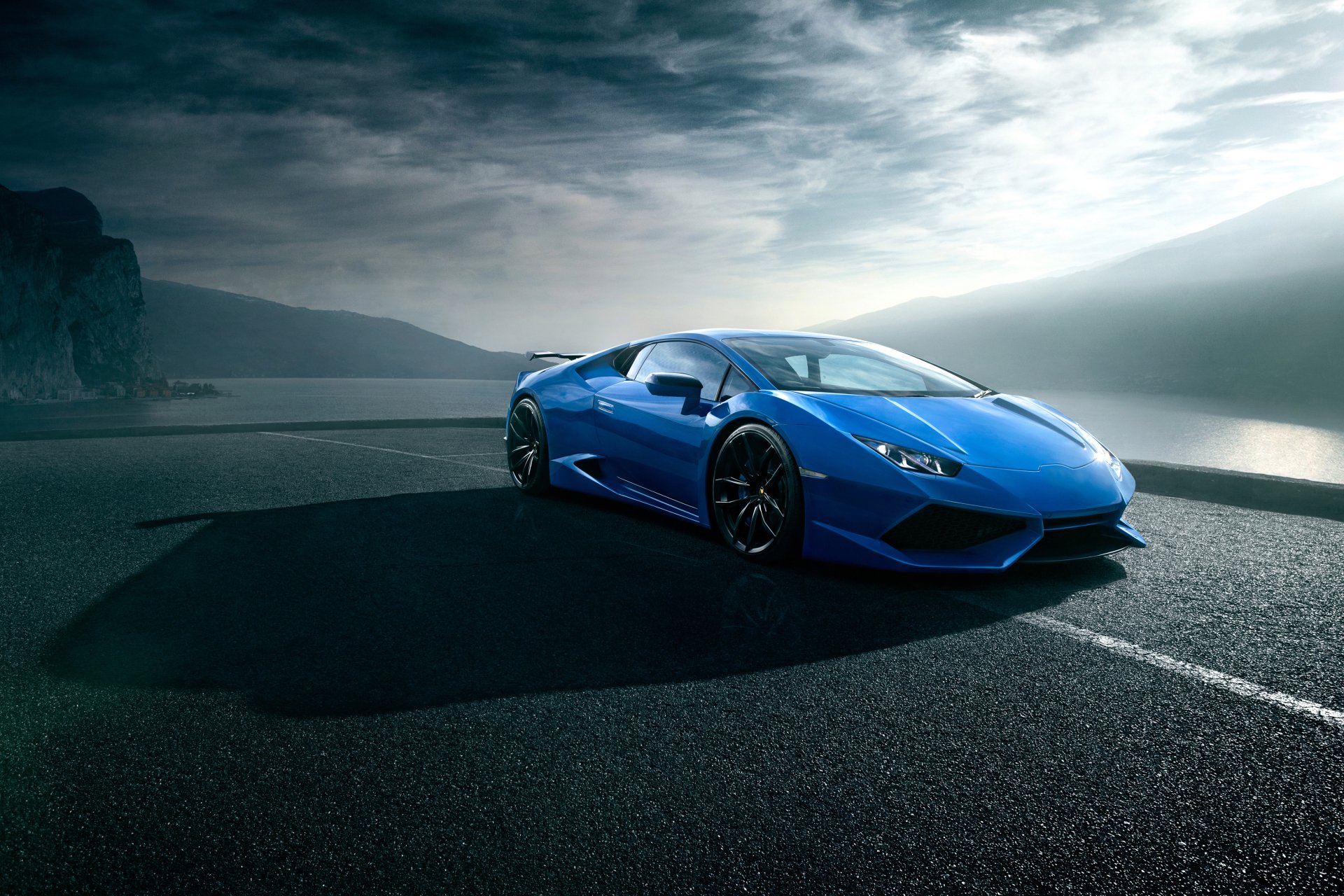 A blue Lamborghini Huracan supercar parked on a scenic coastal road under a cloudy sky, captured in 4K Ultra HD for a PC desktop wallpaper.