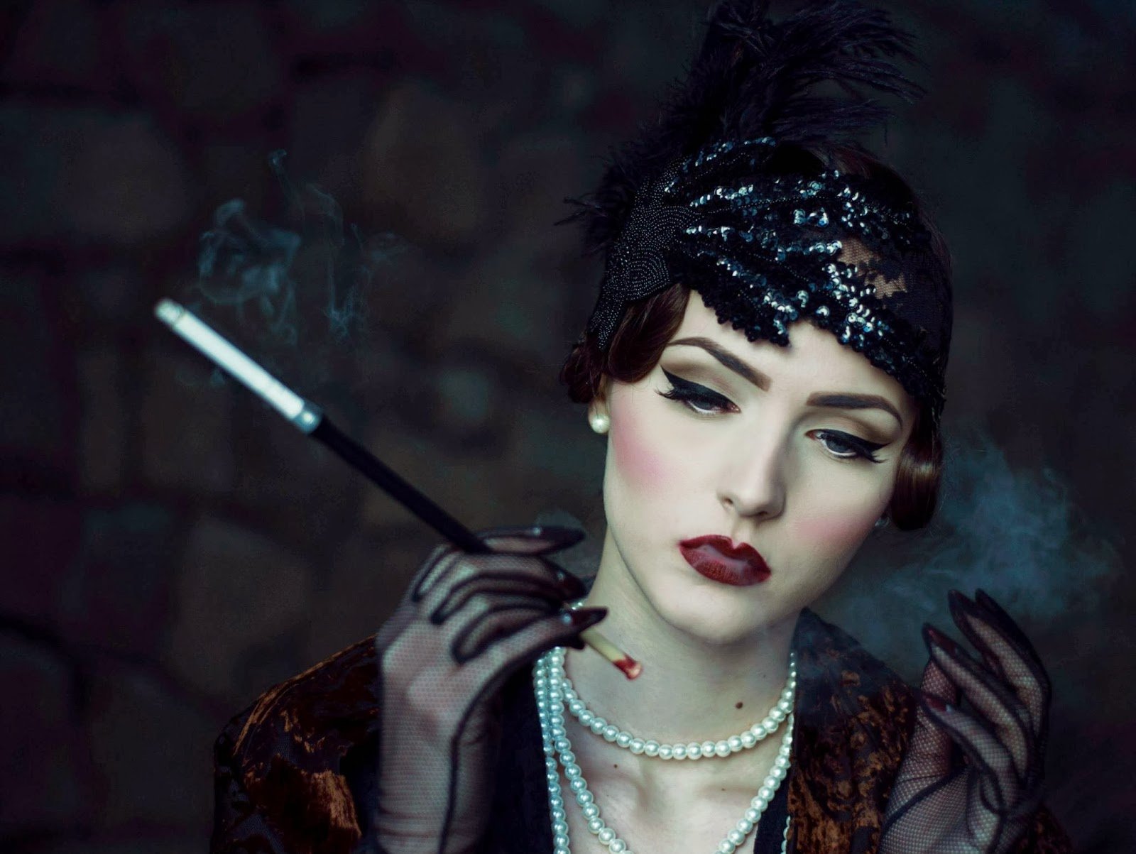 A stylish brunette model wears a statement necklace and bold lipstick while smoking elegantly, capturing a moody, vintage-inspired atmosphere. HD wallpaper for desktop backgrounds.