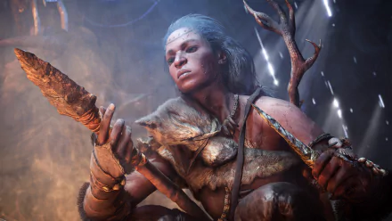 HD PC desktop wallpaper from the video game Far Cry Primal, featuring a fierce tribal warrior holding a primitive weapon in a dramatic, cave-like setting.