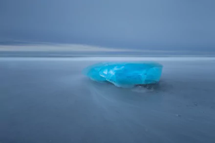 HD desktop wallpaper showing a scenic blue ice formation on a smooth, icy horizon under a calm, muted sky.