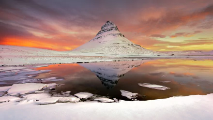 Snow-covered mountain reflected in a calm lake under a vibrant winter sky with clouds, showcasing serene nature in high definition.
