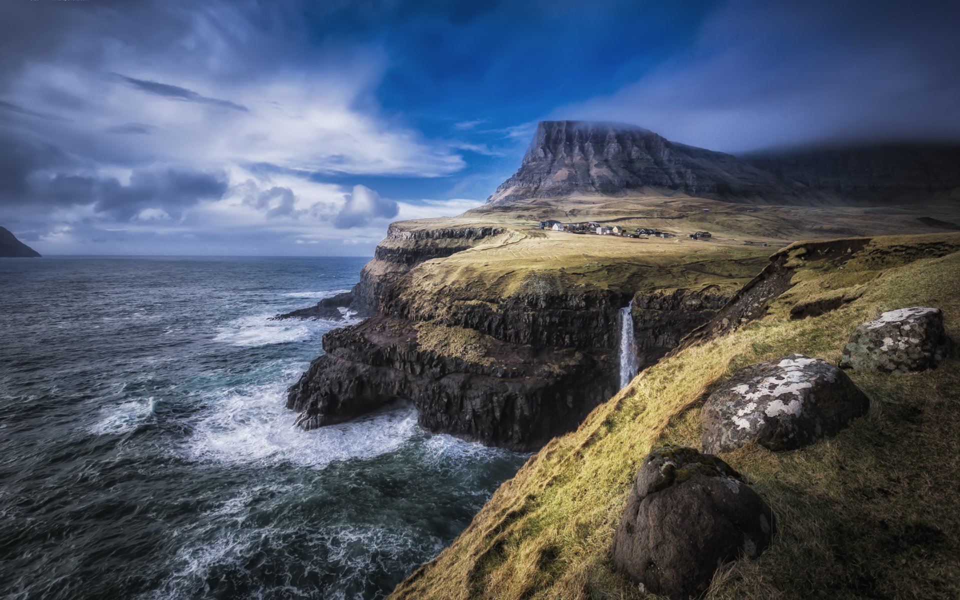 A stunning 4K Ultra HD view of Gásadalur village on the Faroe Islands, featuring dramatic cliffs, a waterfall cascading into the ocean, and a rugged coastline.