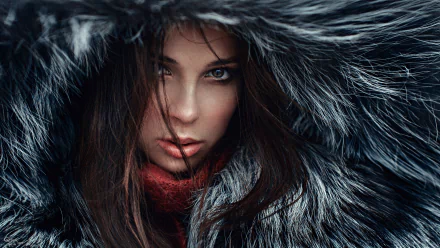HD desktop wallpaper of a brunette woman with brown eyes, partially hidden by dark fur framing her face in a close-up portrait.