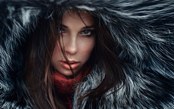 HD desktop wallpaper of a brunette woman with brown eyes, partially hidden by dark fur framing her face in a close-up portrait.