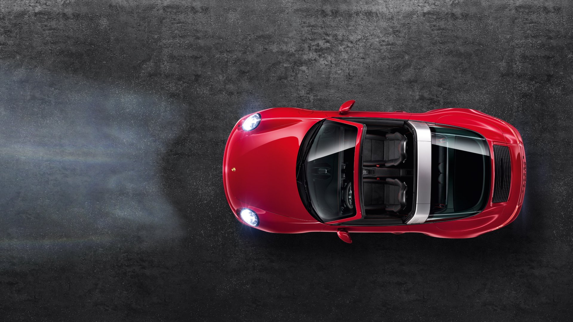 Top-down view of a red Porsche 911 Targa GTS with headlights on, set against a dark textured background in this HD PC desktop wallpaper.