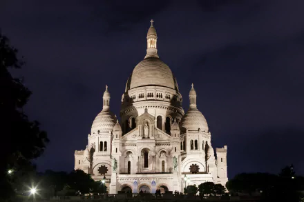 A stunning night view of the Sacré-Cœur Basilica in Paris, showcasing its iconic architecture illuminated against the dark sky. A captivating 4K Ultra HD desktop wallpaper.