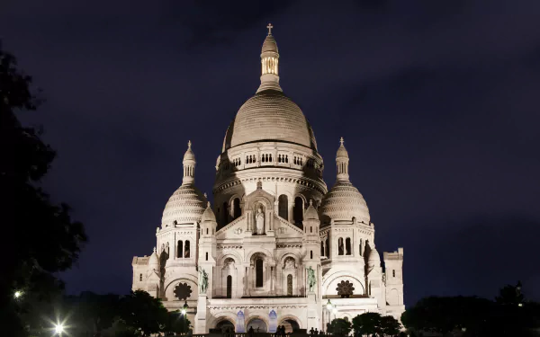 A stunning night view of the Sacré-Cœur Basilica in Paris, showcasing its iconic architecture illuminated against the dark sky. A captivating 4K Ultra HD desktop wallpaper.