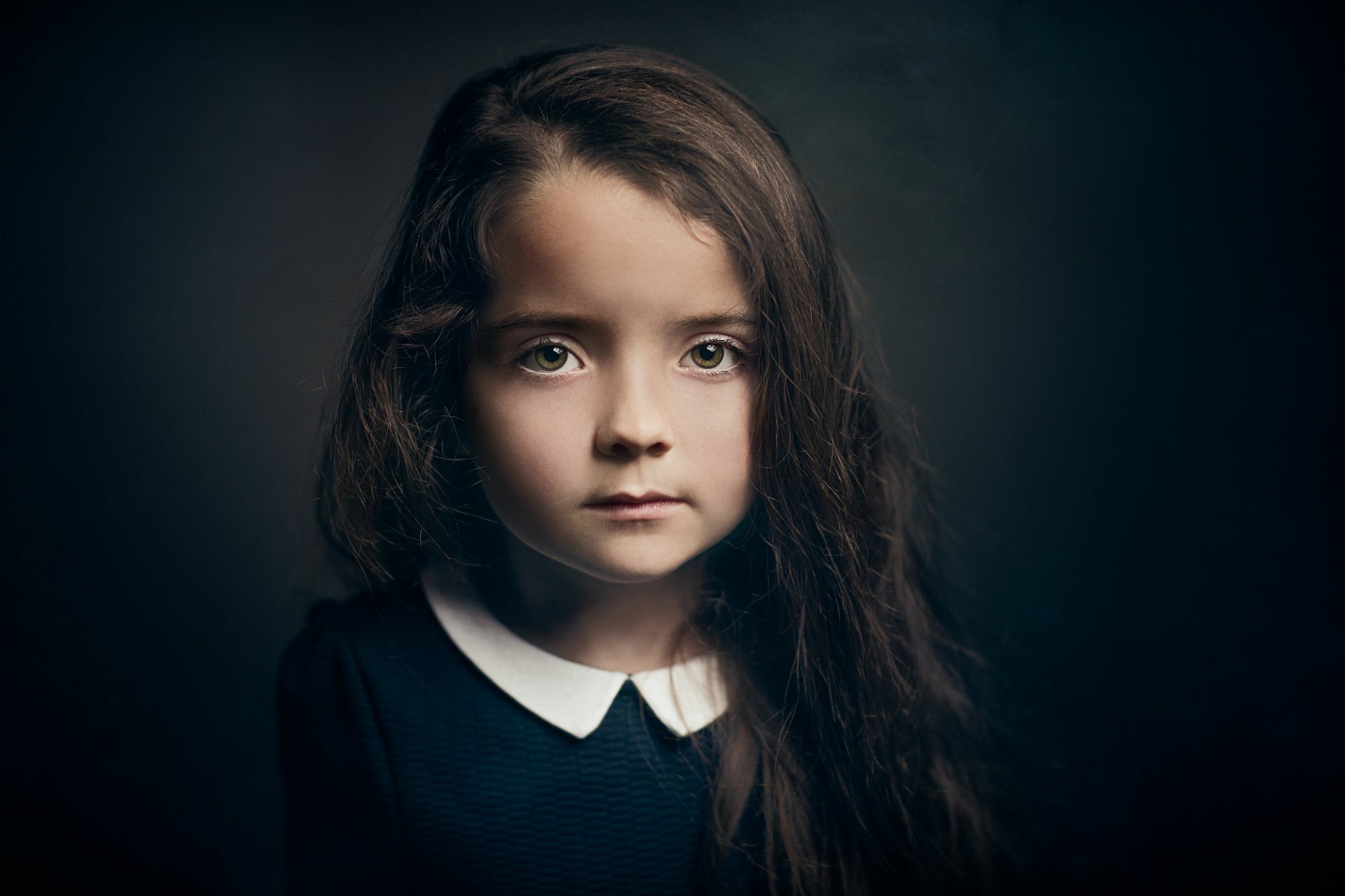HD desktop wallpaper featuring a close-up portrait of a young girl with green eyes, set against a dark background with subtle bokeh effects.