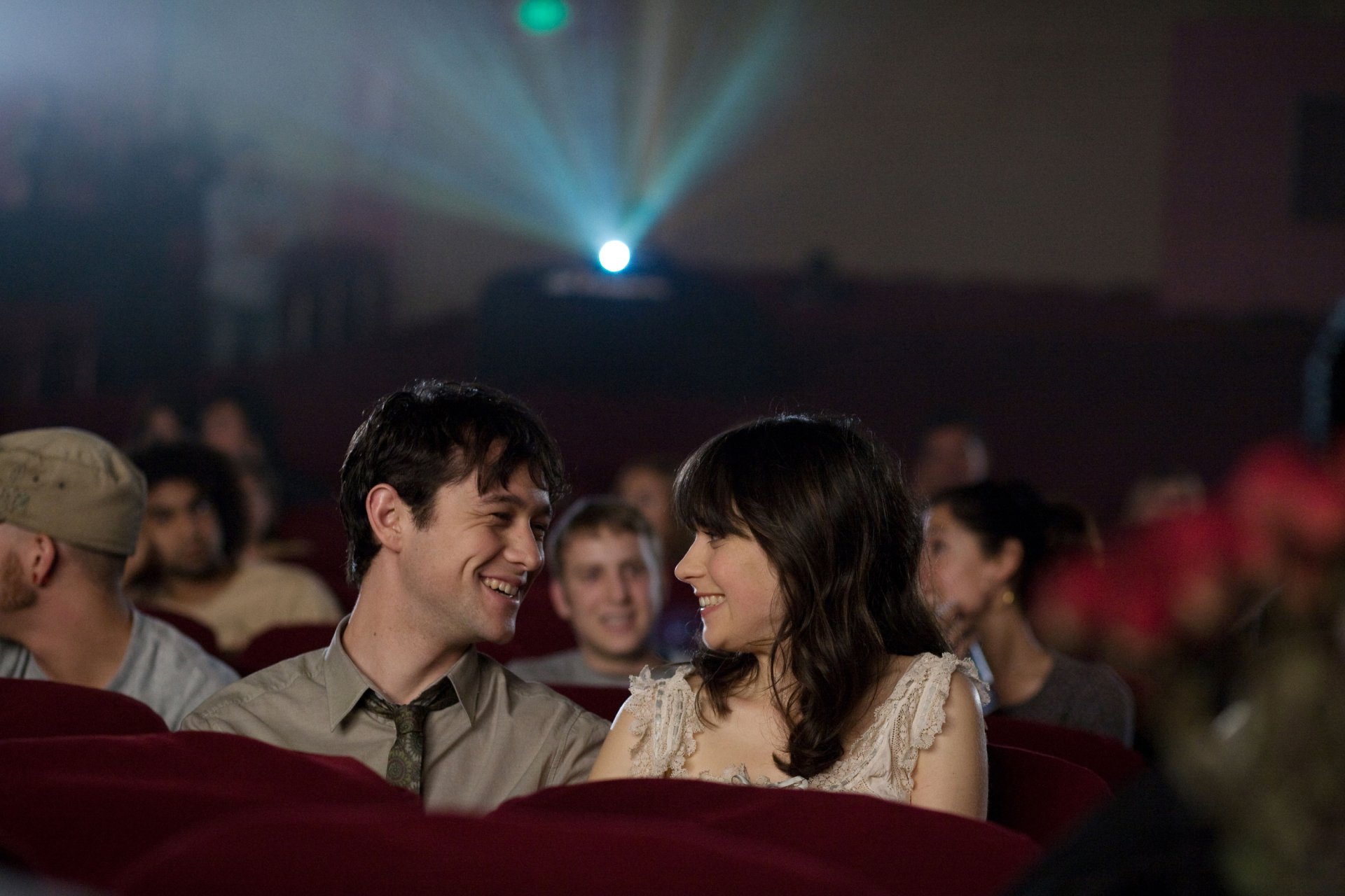 Summer and Tom from 500 Days of Summer sit smiling together in a dim movie theater — 2K Quad HD PC desktop wallpaper.