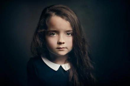 HD desktop wallpaper featuring a close-up portrait of a young girl with green eyes, set against a dark background with subtle bokeh effects.