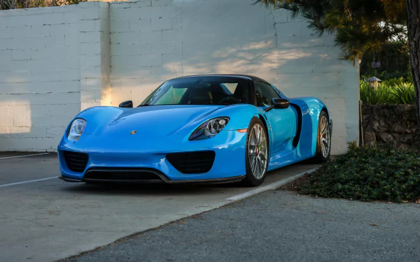 A blue Porsche 918 Spyder supercar parked near a white wall, captured in 4K Ultra HD as a PC desktop wallpaper and background.