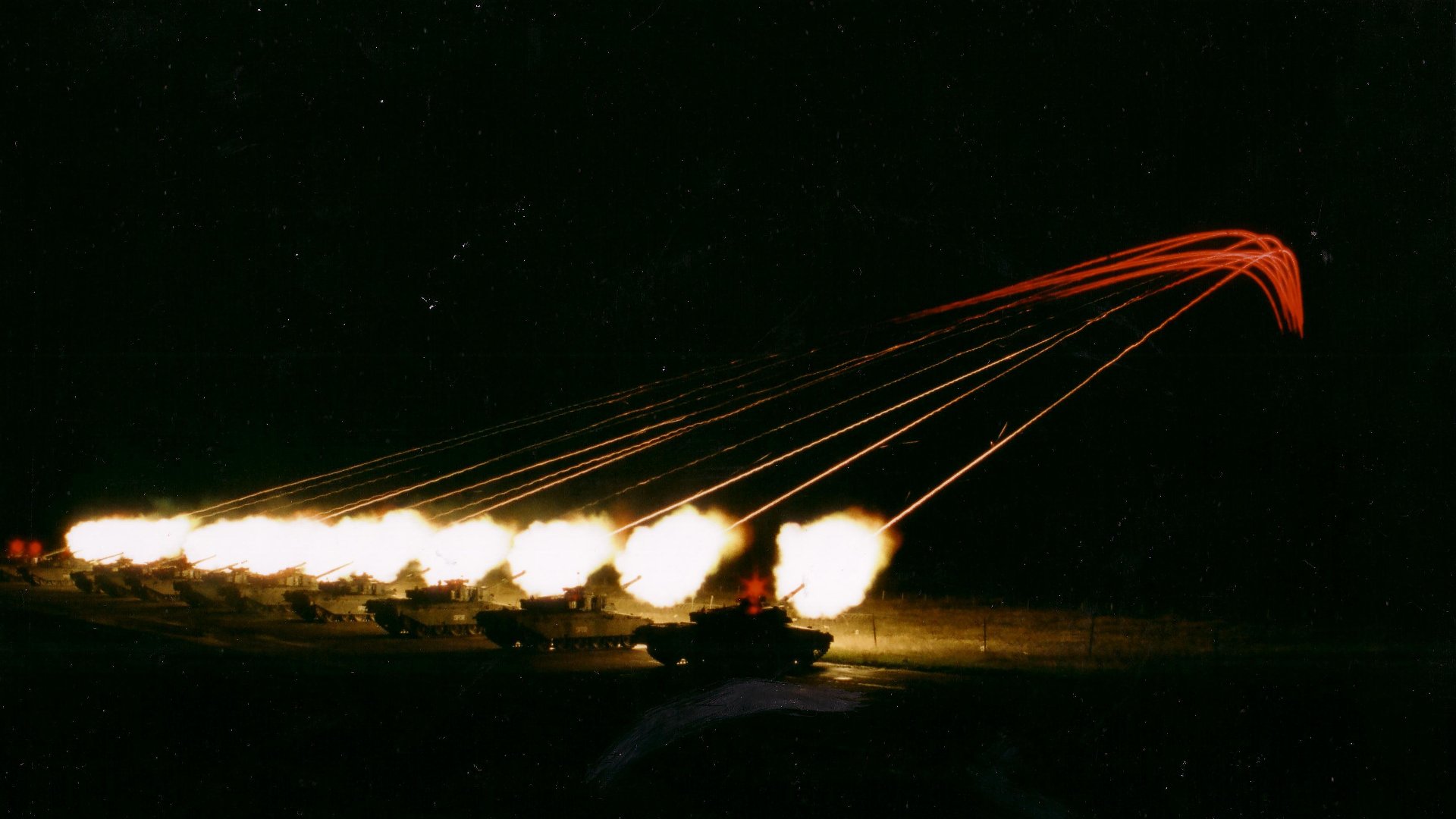 HD desktop wallpaper showing a nighttime military scene with Challenger 1 tanks firing, captured amidst bright explosions and tracer fire streaking across the dark sky.