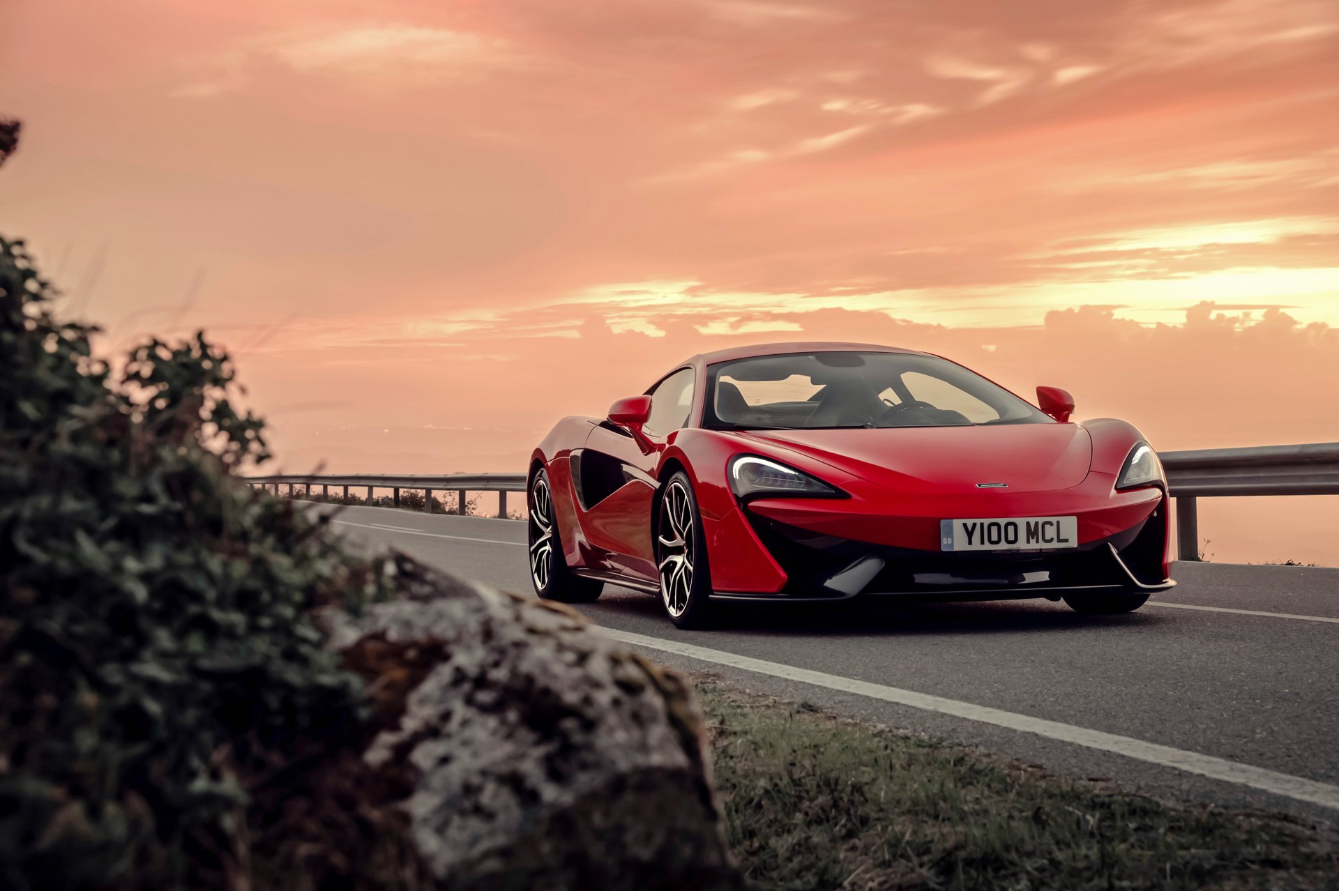 Red McLaren 570S supercar on a scenic road at sunset, captured in 4K Ultra HD for a striking PC desktop wallpaper.