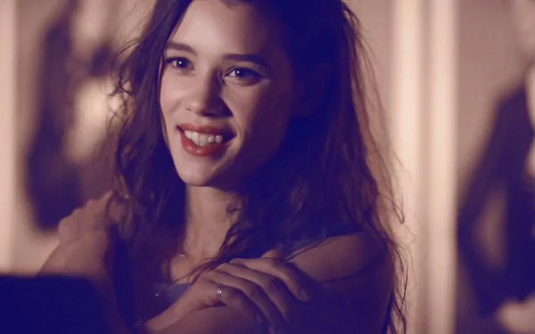 A brunette woman smiles warmly, showcasing her charm as a French model and actress, Astrid Bergès-Frisbey, captured in a vibrant HD wallpaper setting.