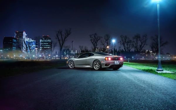 Silver Ferrari 360 Modena supercar parked on a dimly lit road with a city skyline in the background, captured as an HD PC desktop wallpaper.