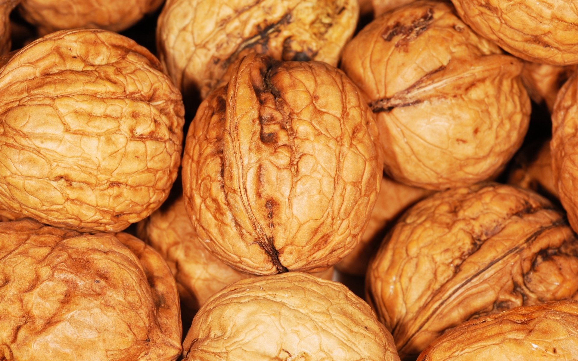 Close-up HD desktop wallpaper of whole walnuts with natural textures, highlighting the nut's detailed shells as a rich food background.