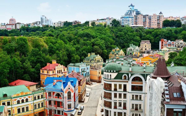 HD PC wallpaper: colorful historic houses and modern buildings on a hillside beside a dense forest in Kyiv, Ukraine, showcasing city and man-made architecture.