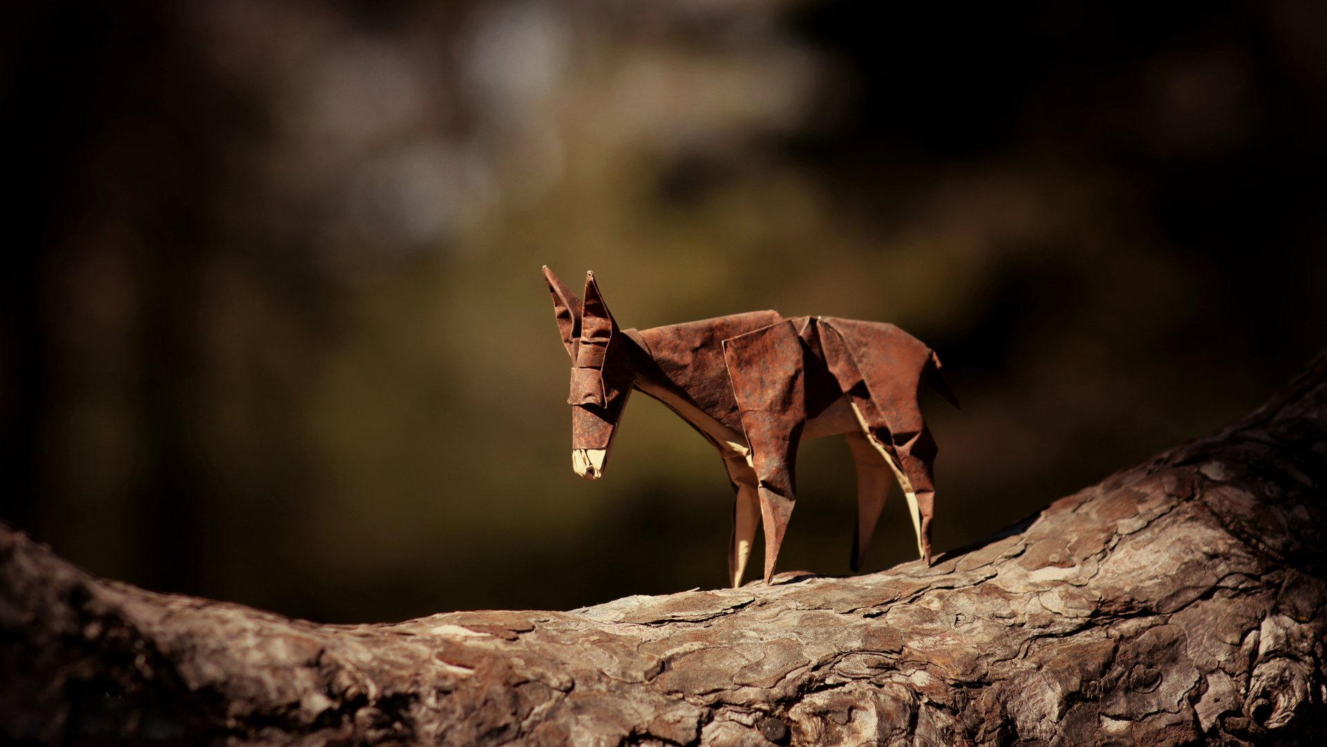 A man-made origami donkey stands on a tree branch with a soft bokeh background, captured in 4K Ultra HD for a detailed desktop wallpaper.