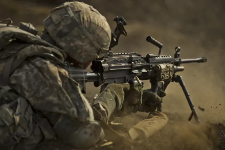A soldier crouches in a dusty environment, gripping a machine gun, showcasing military readiness in this striking 4K Ultra HD desktop wallpaper and background.