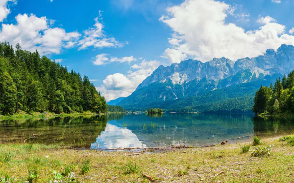 A stunning 8K Ultra HD landscape of a serene lake reflecting a forest, mountains, and a vibrant sky filled with clouds, capturing the beauty of nature.