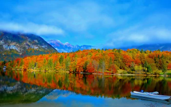 4K Ultra HD desktop wallpaper of a serene lake with a boat, vibrant fall trees, forested mountains, and clouds reflected on the calm water surface.