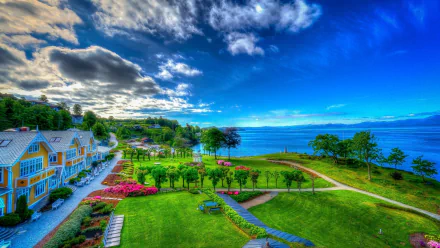 Vibrant HDR desktop wallpaper featuring a colorful tropical resort with hotel buildings, palm trees, manicured gardens, and ocean views under a partly cloudy sky.