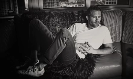 Black and white 4K Ultra HD wallpaper of Canadian actor Ryan Reynolds lying down on a couch, relaxed and casually dressed.
