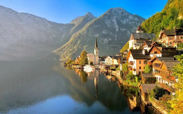 Scenic 4K Ultra HD view of Hallstatt, Austria, featuring a peaceful lake, mountain backdrop, quaint houses, and a church reflecting in the water.