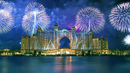 Night view of Atlantis, The Palm in Dubai with spectacular fireworks over the man-made resort, reflected on water — 2K Quad HD PC desktop wallpaper