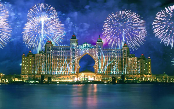 Night view of Atlantis, The Palm in Dubai with spectacular fireworks over the man-made resort, reflected on water — 2K Quad HD PC desktop wallpaper