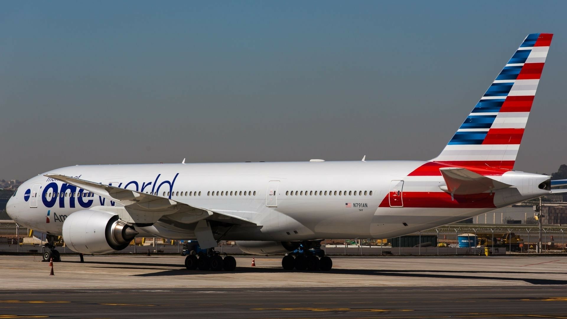 A Boeing 777 passenger plane with an One World livery parked on the tarmac, captured in high definition, showcasing its sleek design and vibrant colors.