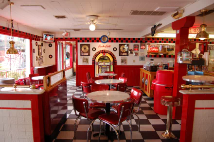 HD desktop wallpaper of a retro-style room featuring a red jukebox, red chairs, tables, and classic diner decor with a checkered floor and vintage accents.