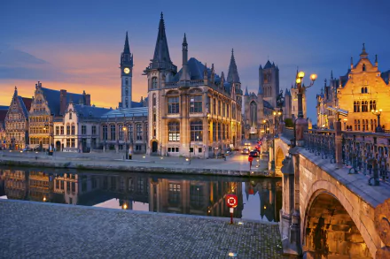 A stunning night view of a Belgium town, featuring a bridge and charming houses reflected in the river under soft lighting, showcasing man-made beauty and serene waterways.