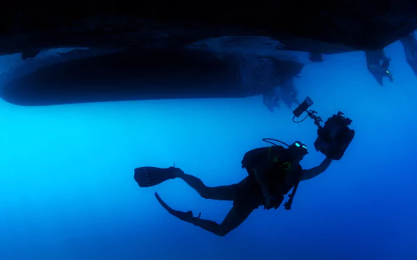 HD underwater image of a scuba diver with a camera exploring the ocean, captured as a vibrant desktop wallpaper showcasing the sport of scuba diving.