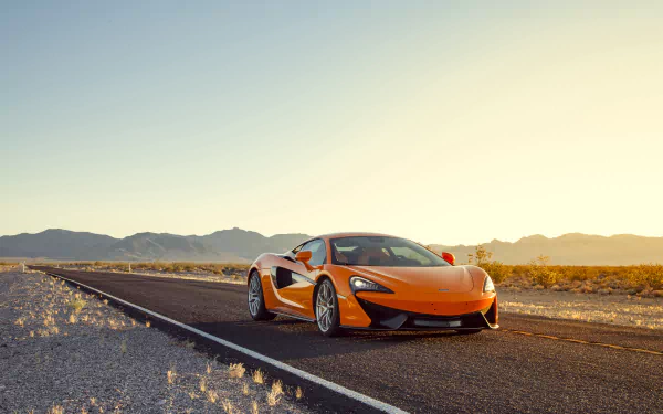Orange McLaren 570S sports car parked on a deserted road at sunset, captured in a 4K Ultra HD desktop wallpaper.