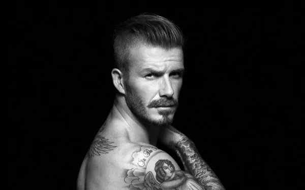 Black and white close-up of David Beckham showcasing his tattoos, captured in a sharp, HD sports-themed portrait.