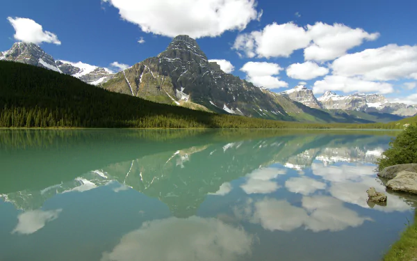 HD desktop wallpaper of Mount Chephren in Banff National Park, Alberta, Canada: mountain and forest reflected in a turquoise lake under clouds and blue sky.