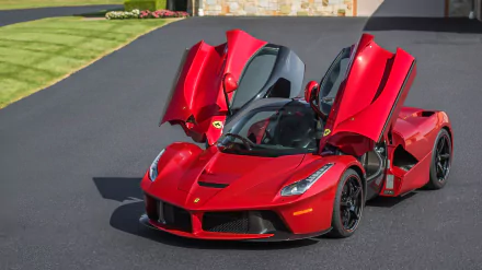 A striking red Ferrari LaFerrari, showcasing its iconic design with doors lifted, parked on a sleek driveway, serving as a stunning HD desktop wallpaper.