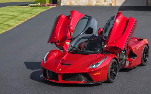 A striking red Ferrari LaFerrari, showcasing its iconic design with doors lifted, parked on a sleek driveway, serving as a stunning HD desktop wallpaper.