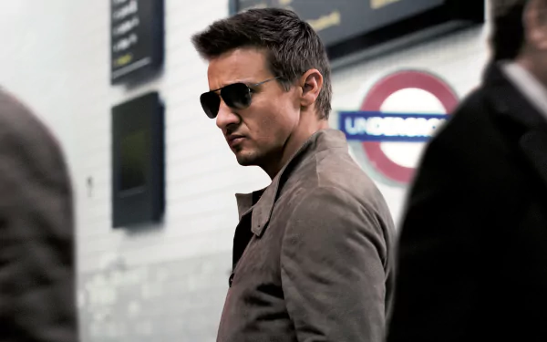 A high-definition wallpaper featuring a character from Mission: Impossible - Rogue Nation, captured in a dynamic moment, wearing sunglasses and a stylish coat, set against a subway backdrop.