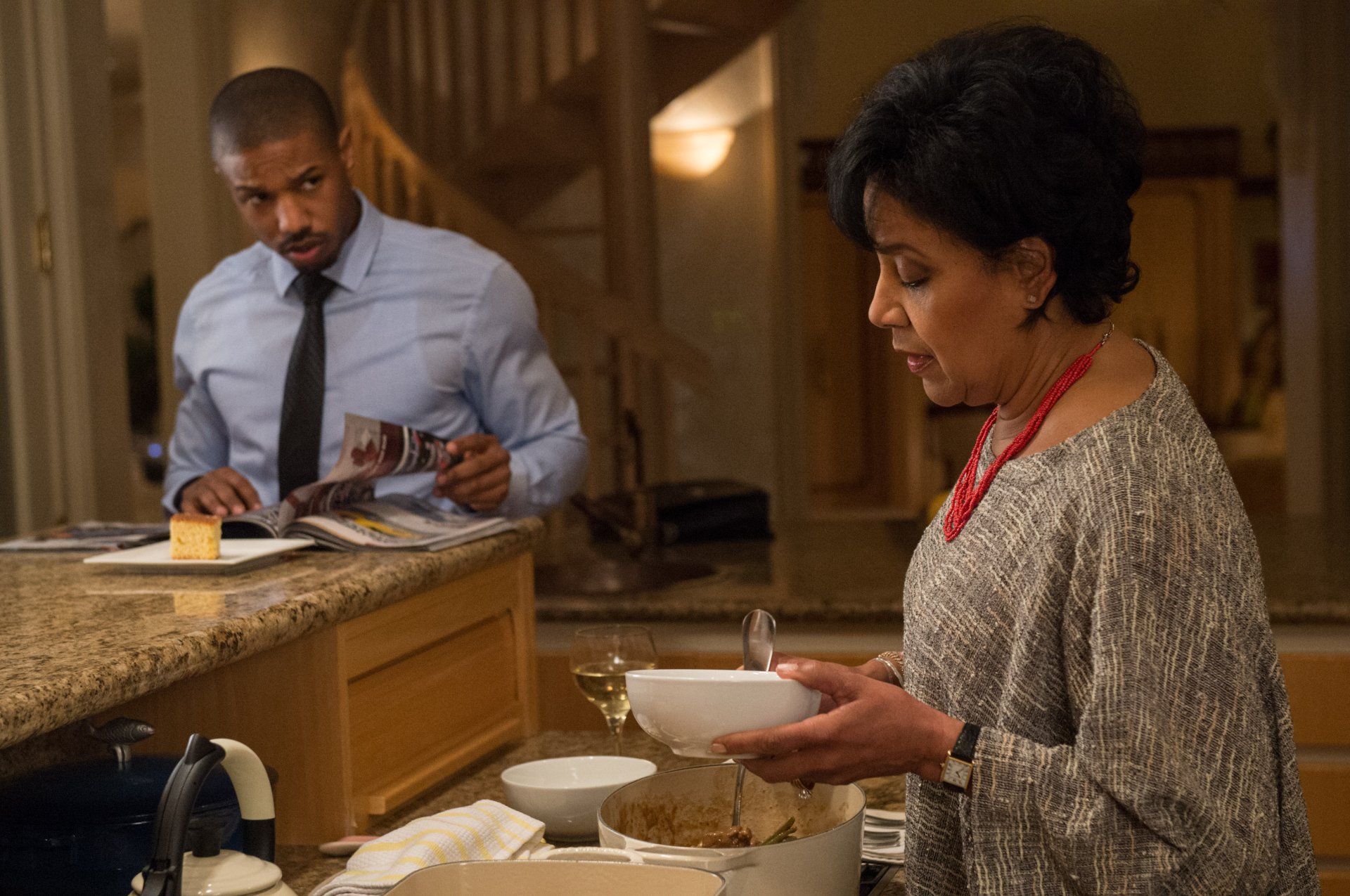 4K PC desktop wallpaper: still from Creed — Adonis Creed and his mother Mary Anne share a quiet kitchen moment; he reads at the counter while she serves food.
