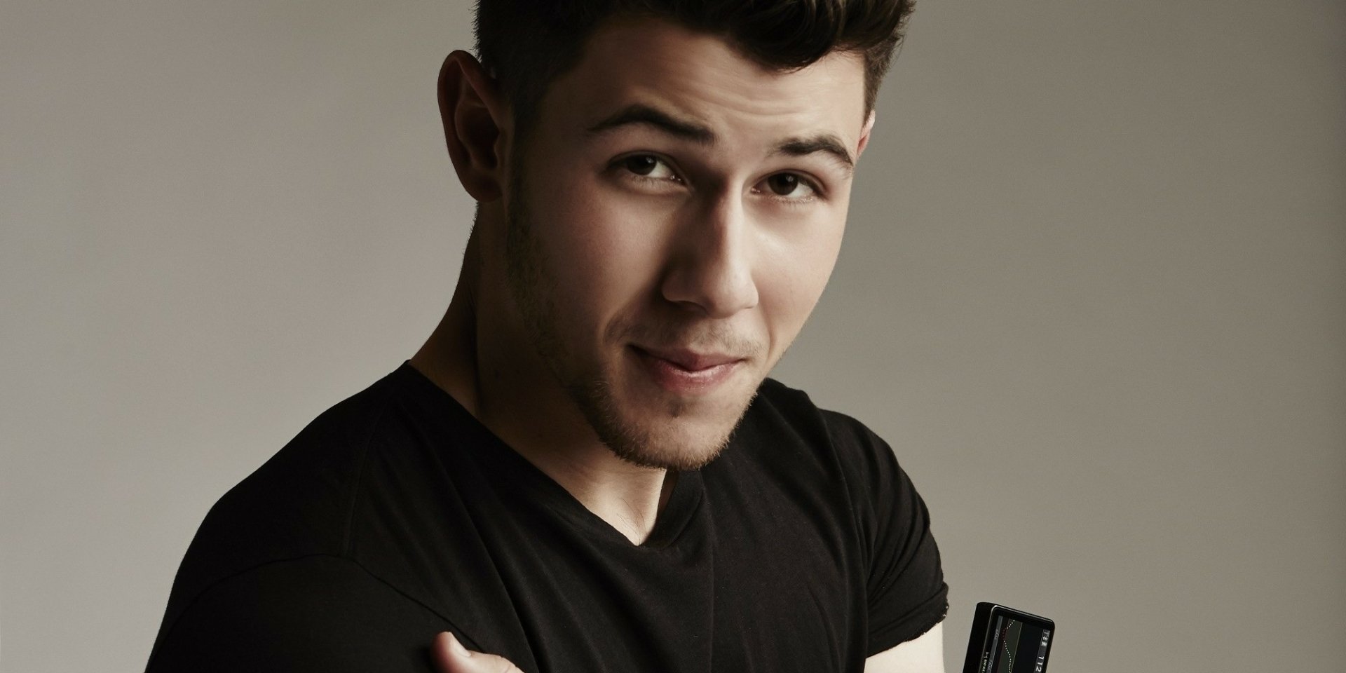HD desktop wallpaper featuring a close-up of a person with a subtle smile, wearing a black shirt on a neutral background.