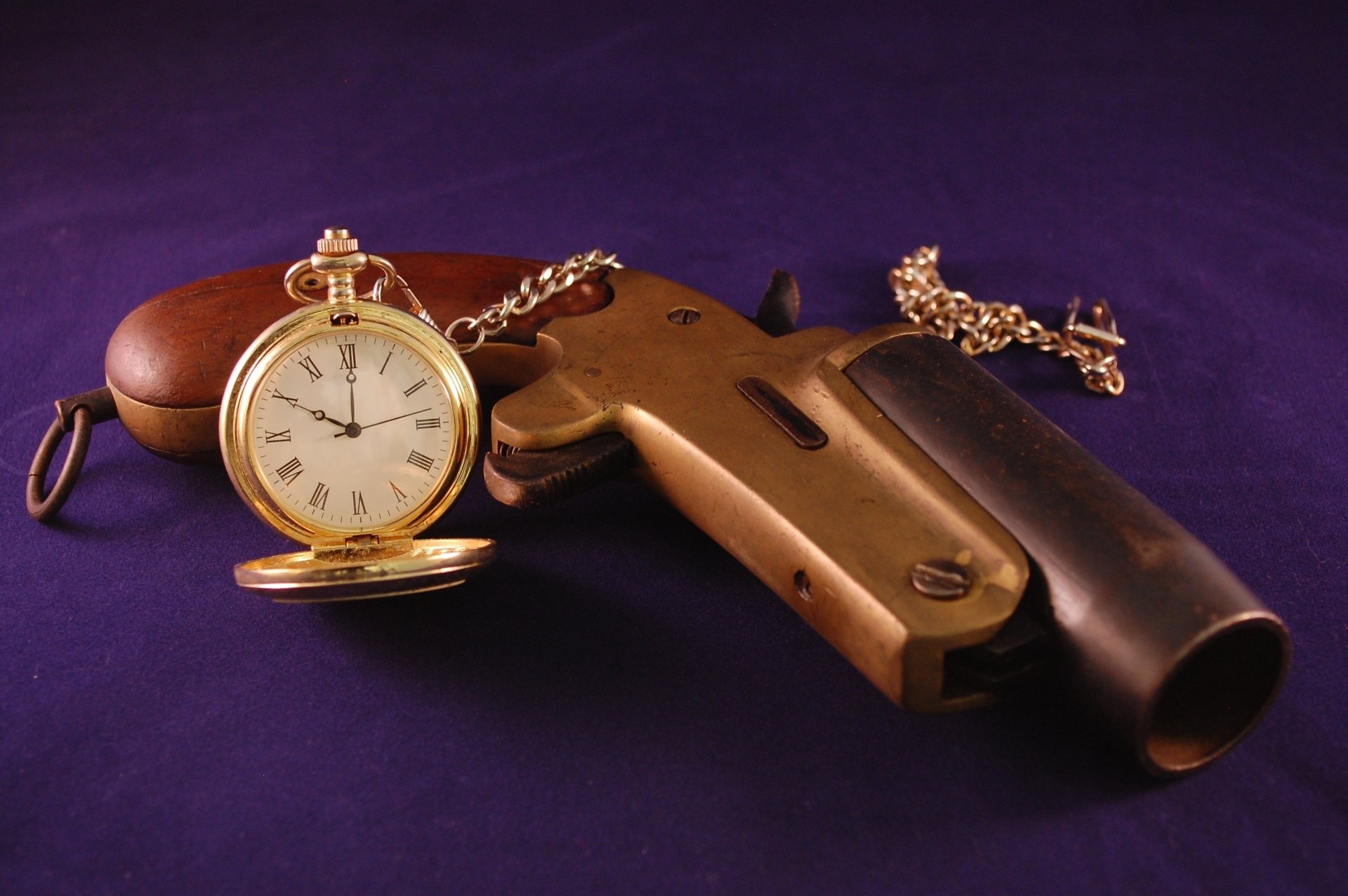 A vintage still life featuring an antique pocket watch resting on a classic gun, set against a rich purple background, captured in HD for desktop wallpaper.