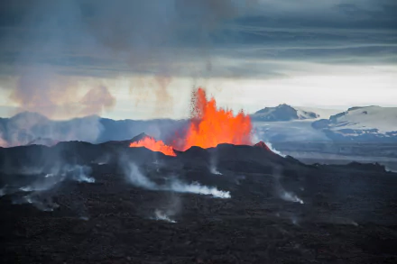 5K Ultra HD PC desktop wallpaper and background: Bárðarbunga eruption in Iceland — glowing lava fountains and smoke over a dark volcanic field with distant ice-covered peaks.