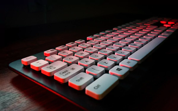 A close-up view of a modern keyboard illuminated with red lighting, set against a dark background, creating a striking technology-themed HD desktop wallpaper.