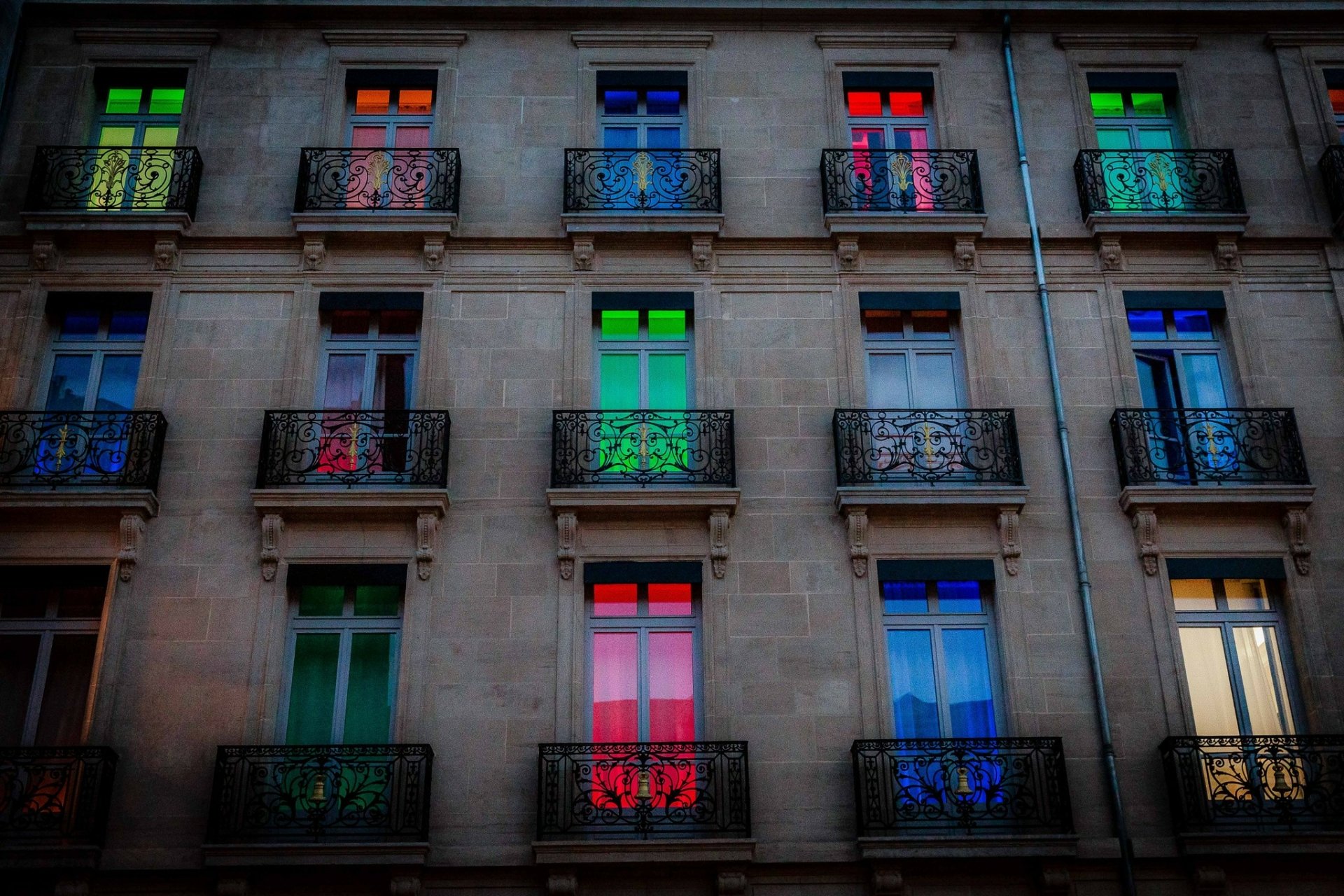 Colorful windows illuminate a hotel in Dijon, France, showcasing a vibrant display of light and color on its elegant facade. This HD wallpaper captures the essence of man-made beauty.