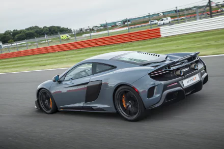 McLaren 675LT supercar in motion on a racetrack, showcased in a sharp 4K Ultra HD desktop wallpaper capturing the sleek design and performance of this luxury vehicle.