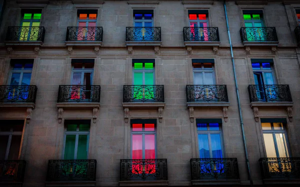 Colorful windows illuminate a hotel in Dijon, France, showcasing a vibrant display of light and color on its elegant facade. This HD wallpaper captures the essence of man-made beauty.
